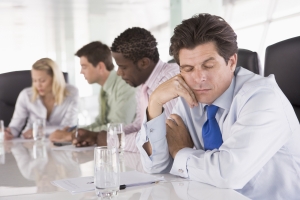 A man during a meeting wastes time by not paying attention.