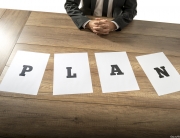 man sits in front of paper that says plan