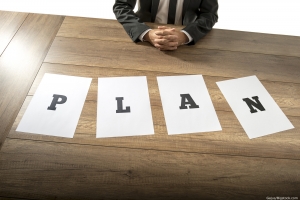 man sits in front of paper that says plan