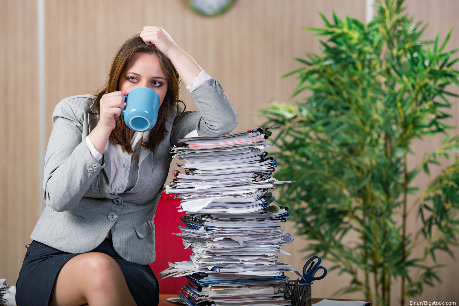 woman sitting next to a stack of paperwork